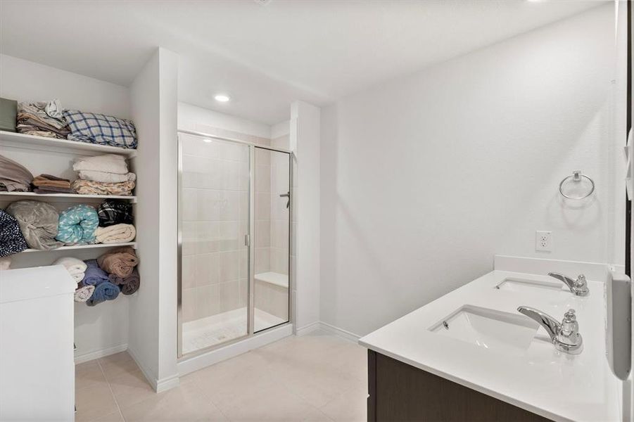 Full bathroom featuring double vanity, light tile patterned floors, a shower stall, and recessed lighting
