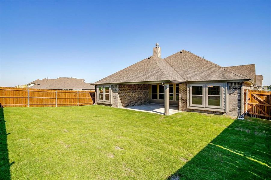 Rear view of property with a lawn and a patio