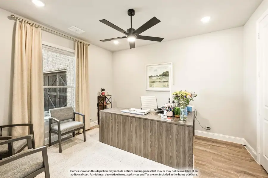 Home office with wood desk, ceiling fan, hardwood floors, and large window with curtains