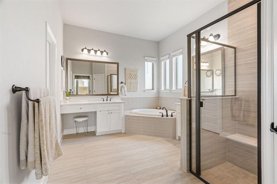 Bathroom featuring a dual vanity with white cabinetry, a built-in soaking tub, and a separate shower enclosure with a built-in bench Bathroom featuring a dual vanity with white cabinetry, a built-in soaking tub, and a separate shower enclosure with a built-in bench