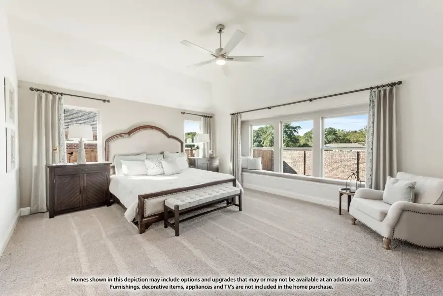 Spacious master bedroom with vaulted ceiling, ceiling fan, window seat, and neutral carpet flooring