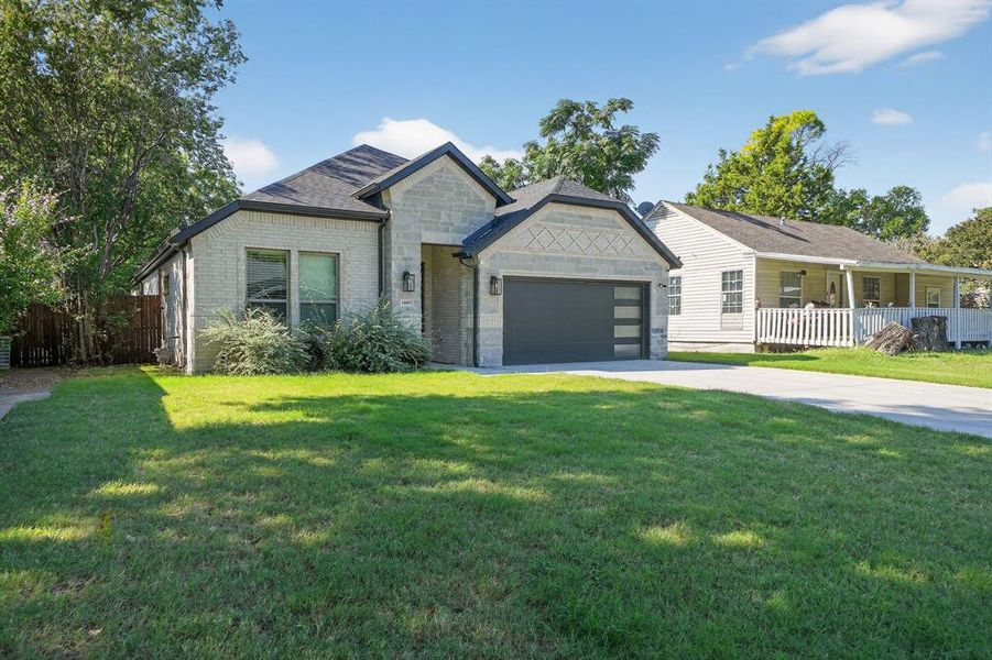 View of front facade with concrete driveway, brick siding, an attached garage, and stone siding