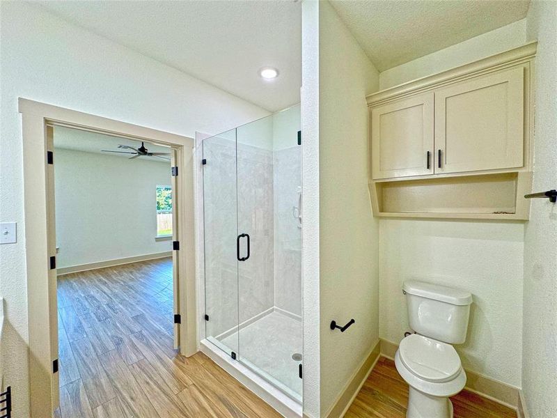 Full bath with light wood-type flooring, a shower stall, and a ceiling fan Full bath with light wood-type flooring, a shower stall, and a ceiling fan