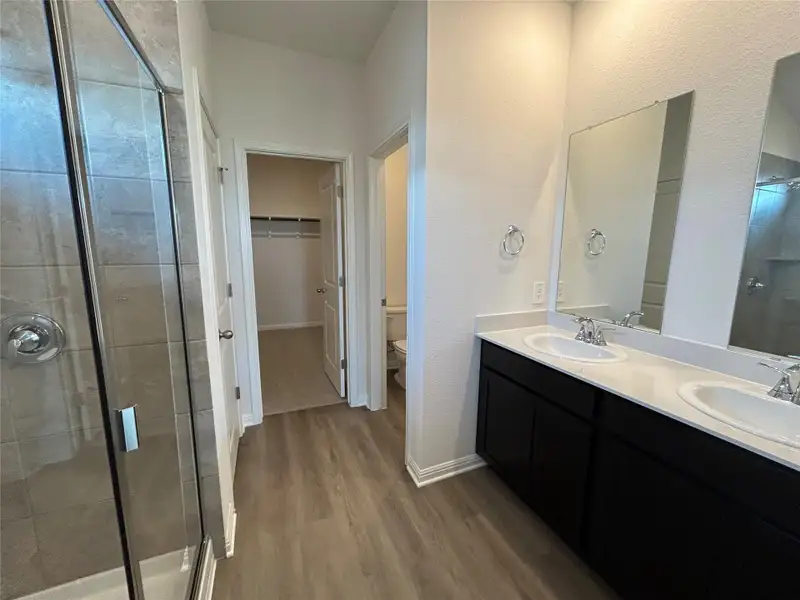 Bathroom with a stall shower, dark wood-type flooring, double vanity, and a spacious closet Bathroom with a stall shower, dark wood-type flooring, double vanity, and a spacious closet