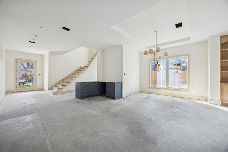 DINING ROOM - Open sightlines connect the living and dining areas, with a modern chandelier defining the dining zone and clean architectural lines guiding movement throughout the main level. Thoughtful spacing and ceiling detail allow flexibility for everyday living while maintaining a polished, cohesive flow. -- Construction as of 1/5/26