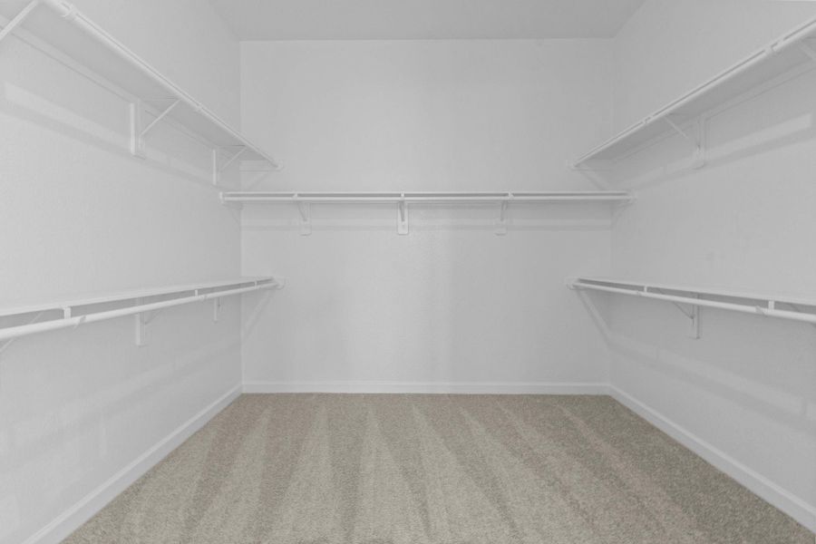 Expansive walk-in closet with built-in shelving and ample space for organization, offering both style and convenience.