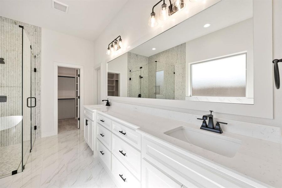 Bathroom featuring a shower stall, double vanity, a walk in closet, and light marble finish flooring