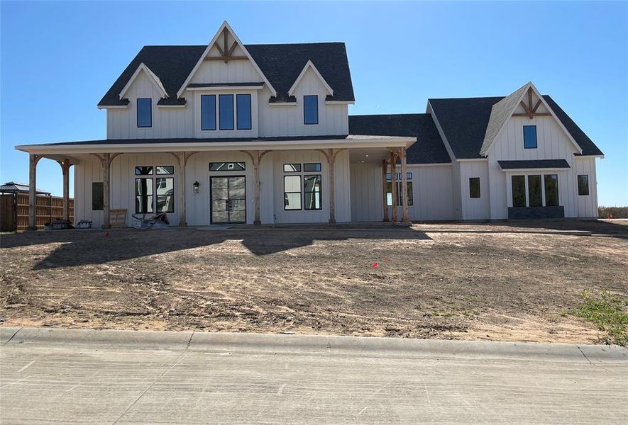 Modern farmhouse featuring covered porch, a shingled roof, and board and batten siding Modern farmhouse featuring covered porch, a shingled roof, and board and batten siding