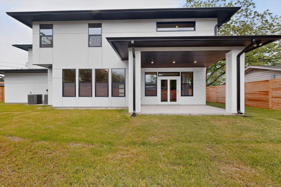 Modern architecture with expansive windows opens to a covered patio and private backyard.