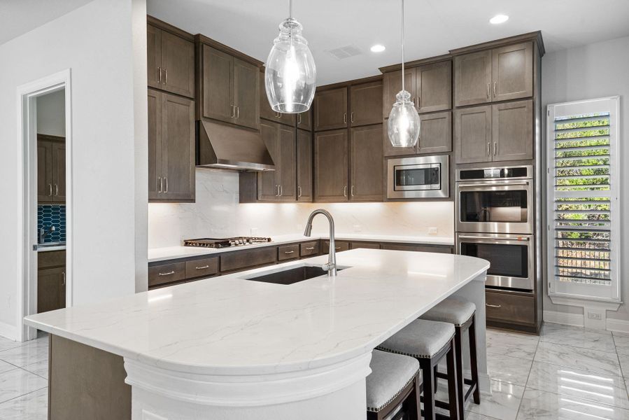 Kitchen featuring light marble finish flooring, light stone countertops, and dark wood finish cabinetry