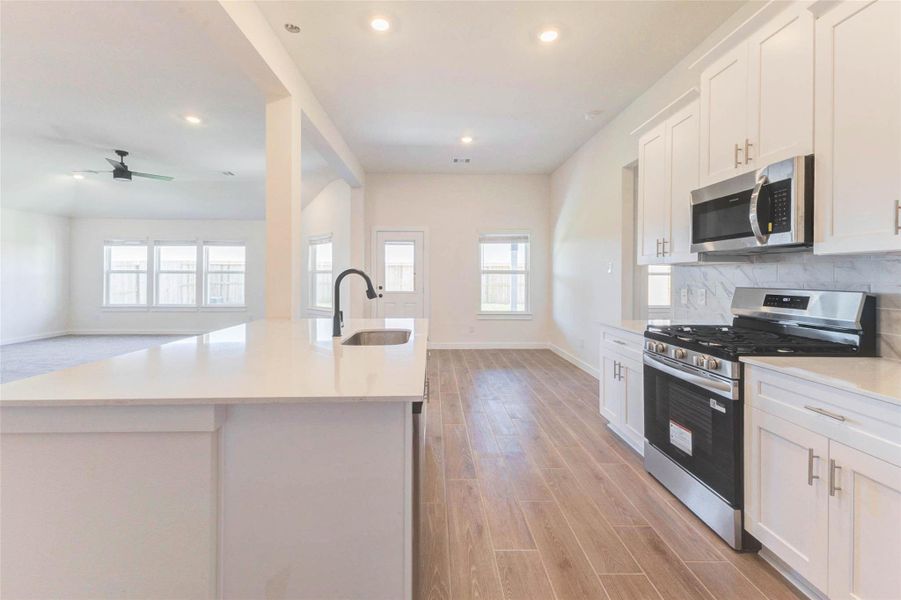 Modern kitchen featuring quartz countertops, oversized island, breakfast bar seating, and open layout to the family room.