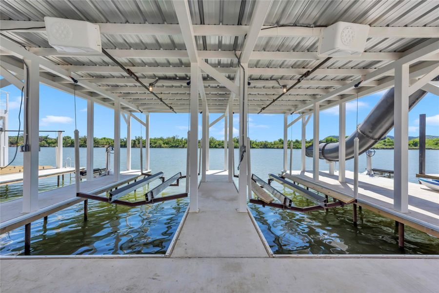 Double boat slips with mechanical lifts sit securely covered beneath a metal canopy.