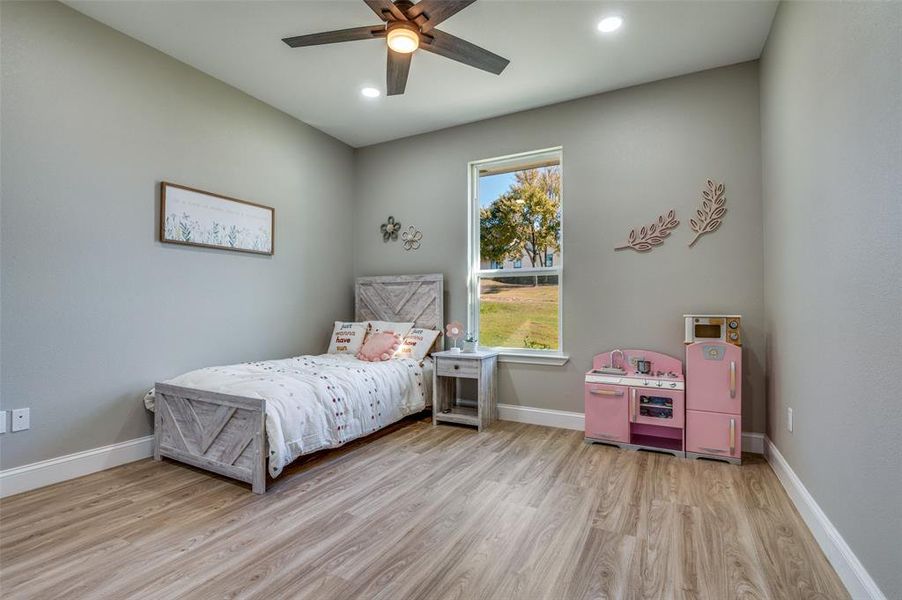 Bedroom with light wood-style floors, ceiling fan, and recessed lighting