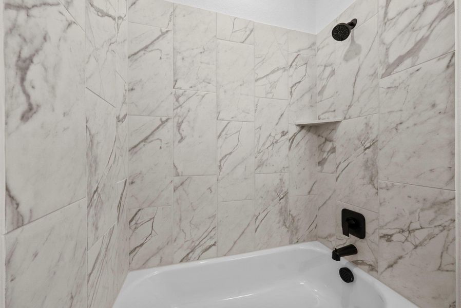 Tub and shower combination with elegant marble-look tile surround.