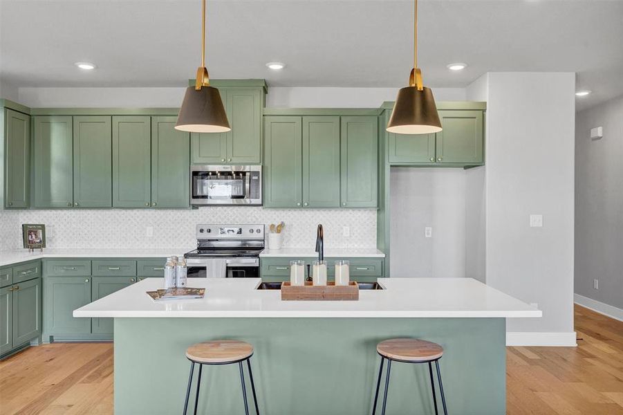 Kitchen with green cabinetry, backsplash, stainless steel appliances, a kitchen breakfast bar, and recessed lighting Kitchen with green cabinetry, backsplash, stainless steel appliances, a kitchen breakfast bar, and recessed lighting