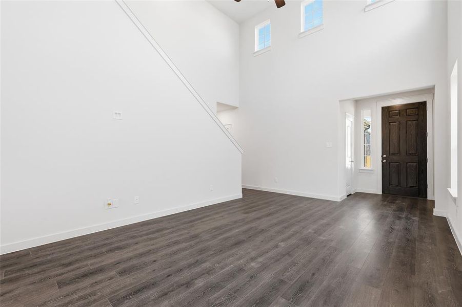 Entryway featuring a dark paneled door, high ceilings, upper transom windows, wood-finish flooring, and a staircase with white risers