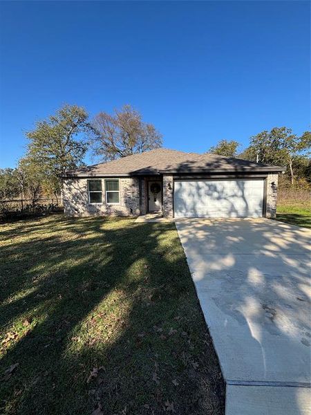 Single story home featuring driveway, a front yard, an attached garage, brick siding, and roof with shingles Single story home featuring driveway, a front yard, an attached garage, brick siding, and roof with shingles