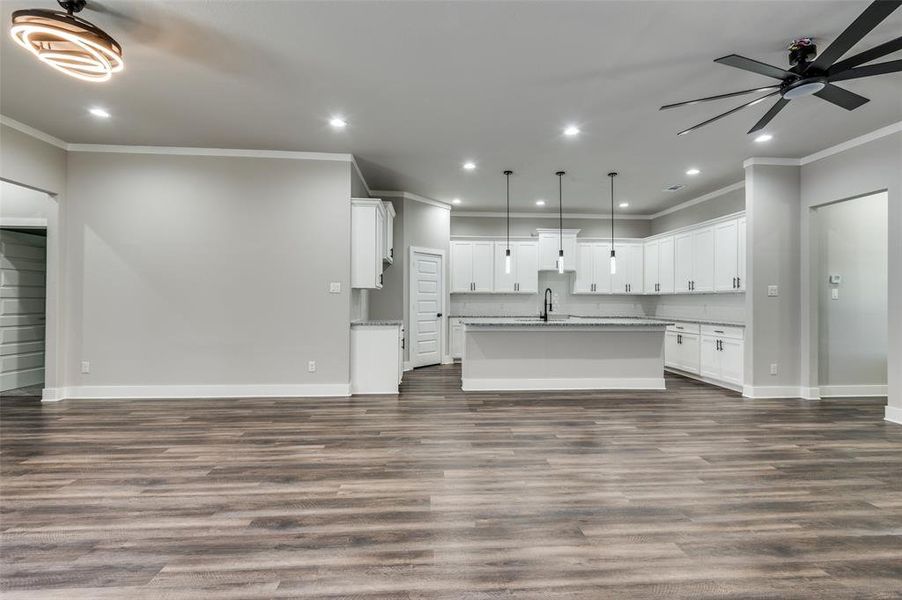 Unfurnished living room with ornamental molding, recessed lighting, ceiling fan, and dark wood-style floors Unfurnished living room with ornamental molding, recessed lighting, ceiling fan, and dark wood-style floors