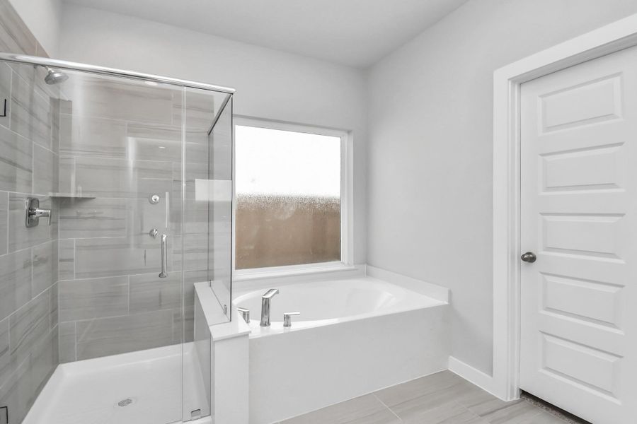 Indulge in a spa-like retreat within the confines of this primary bathroom. Delight in a spacious walk-in shower enveloped in stylish tile surround and unwind in a separate garden tub adorned with custom detailing. Indulge in a spa-like retreat within the confines of this primary bathroom. Delight in a spacious walk-in shower enveloped in stylish tile surround and unwind in a separate garden tub adorned with custom detailing.
