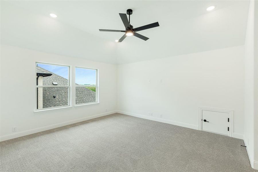 Empty bedroom with gray carpet, black ceiling fan, white walls, and two windows