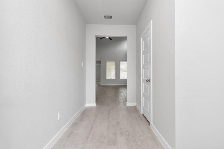 The grand entrance beckons with high ceilings, adorned with elegant wood-look tile flooring and oversized baseboards. Sample photo of completed home with similar floor plan. Actual colors and selections may vary.