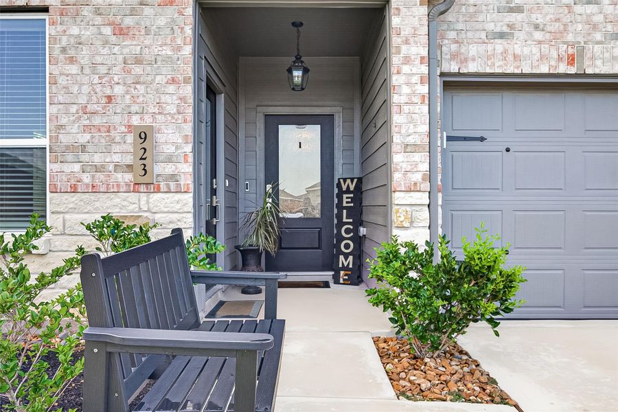 Covered front entry with landscaped surroundings and an inviting seating area, featuring two separate doors—one providing direct access to the private guest suite and the other leading into the main home. Covered front entry with landscaped surroundings and an inviting seating area, featuring two separate doors—one providing direct access to the private guest suite and the other leading into the main home.