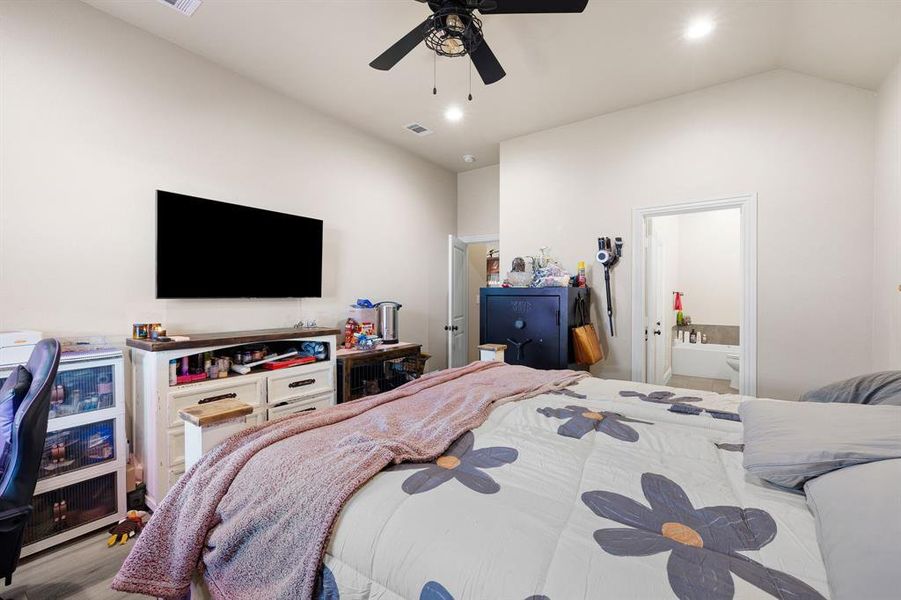 Bedroom featuring ceiling fan, ensuite bathroom, lofted ceiling, and light hardwood / wood-style floors