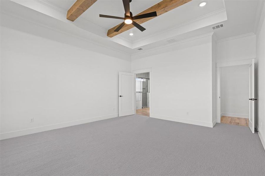 Unfurnished bedroom featuring a ceiling fan, carpet flooring, crown molding, a towering ceiling, and beamed ceiling