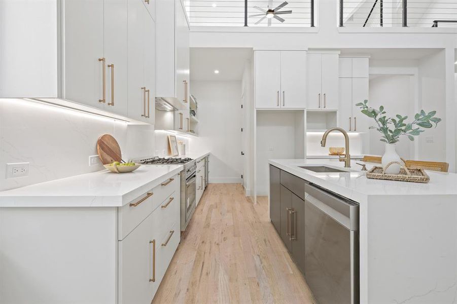 Kitchen with custom range hood, appliances with stainless steel finishes, sink, white cabinetry, and light hardwood / wood-style floors