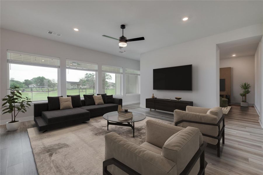 Expansive living area featuring light-tone wood-finish flooring, recessed lighting, and a dark-tone ceiling fan