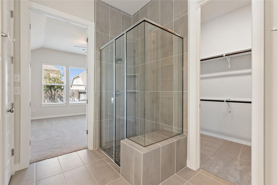 Bathroom with light carpet, a shower stall, light tile patterned flooring, and vaulted ceiling