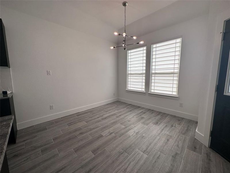 Unfurnished dining area with dark hardwood / wood-style flooring, a chandelier, and vaulted ceiling