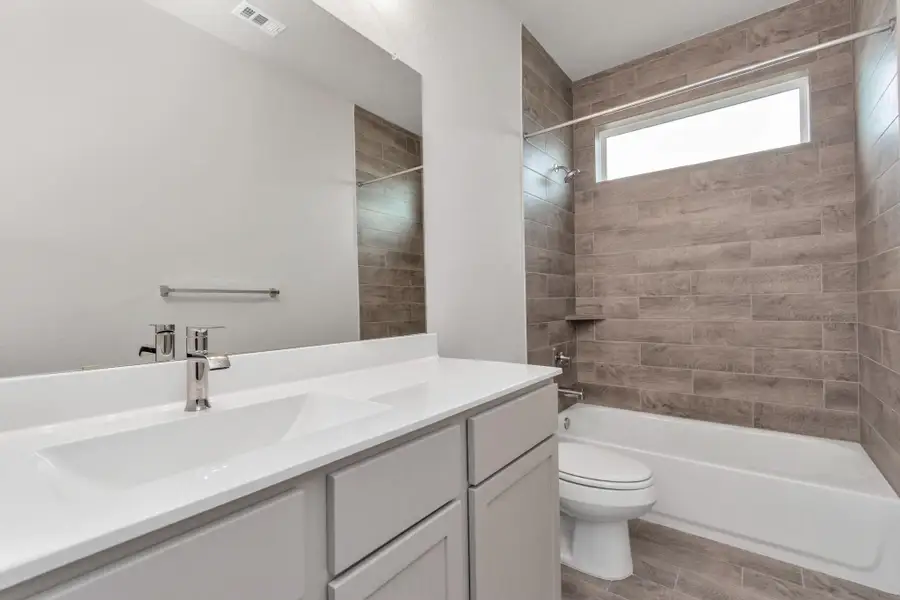 Secondary bath, adjacent to the bedroom at the front of your home. Tub and shower combo with tile surround adorned with a stylish vanity, and modern hardware. Sample photo of completed home with similar floor plan. Actual colors and selections may vary. Secondary bath, adjacent to the bedroom at the front of your home. Tub and shower combo with tile surround adorned with a stylish vanity, and modern hardware. Sample photo of completed home with similar floor plan. Actual colors and selections may vary.