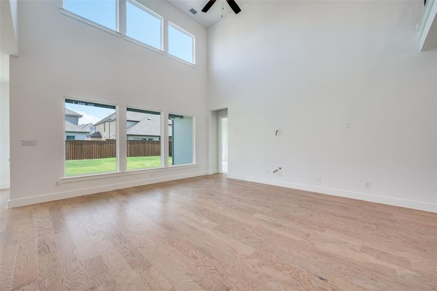 Unfurnished room featuring light hardwood / wood-style flooring, ceiling fan, and a towering ceiling