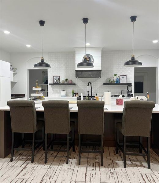 Kitchen featuring backsplash, sink, pendant lighting, kitchen peninsula, and a breakfast bar