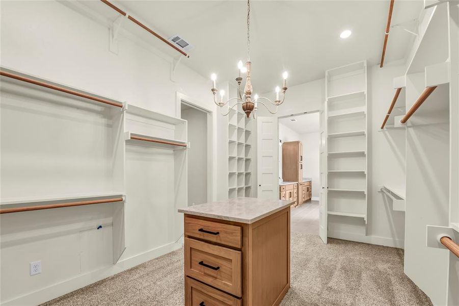 Spacious closet with a chandelier and light carpet