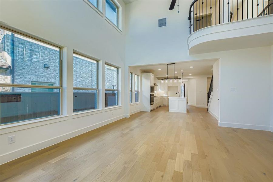 Unfurnished living room featuring light wood-style flooring and a high ceiling