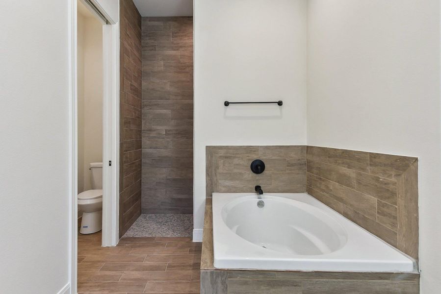 Full bathroom with tiled shower, toilet, and a bath Full bathroom with tiled shower, toilet, and a bath