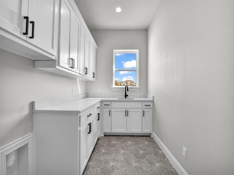 Kitchen featuring light stone countertops, sink, white cabinets, and light tile patterned floors