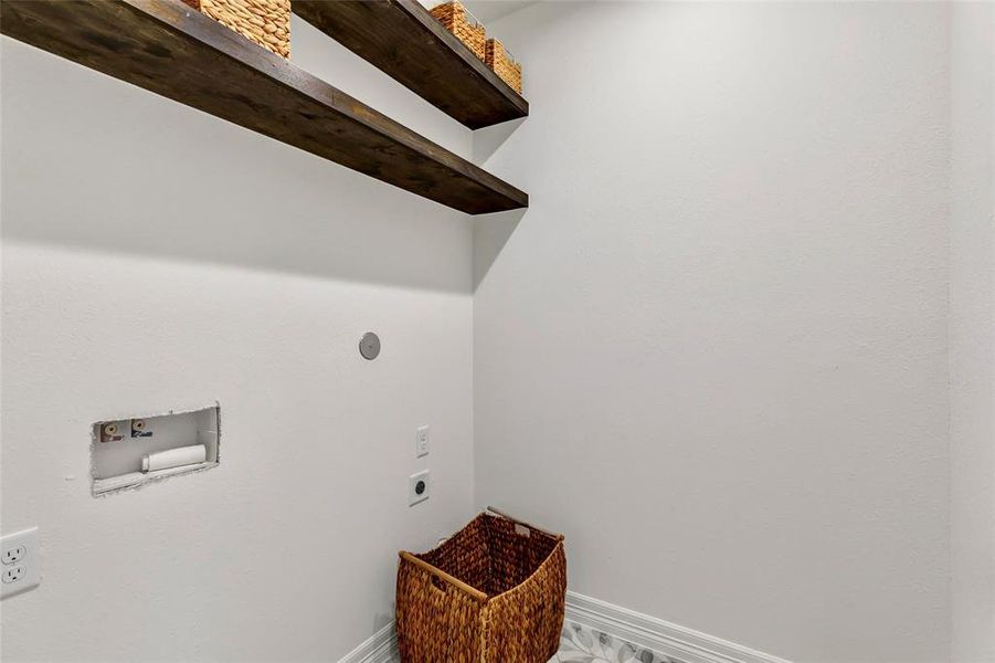 Spacious laundry room featuring convenient overhead shelving.