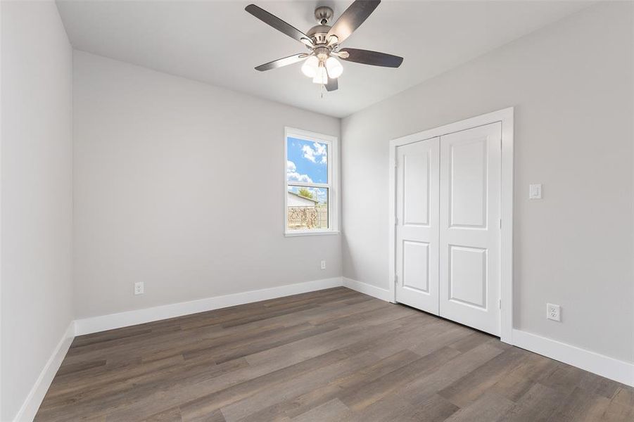 Unfurnished bedroom featuring ceiling fan, a closet, and hardwood / wood-style flooring