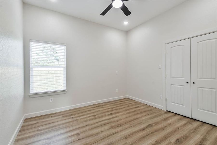 Third bedroom with large closet and remote control ceiling fan.