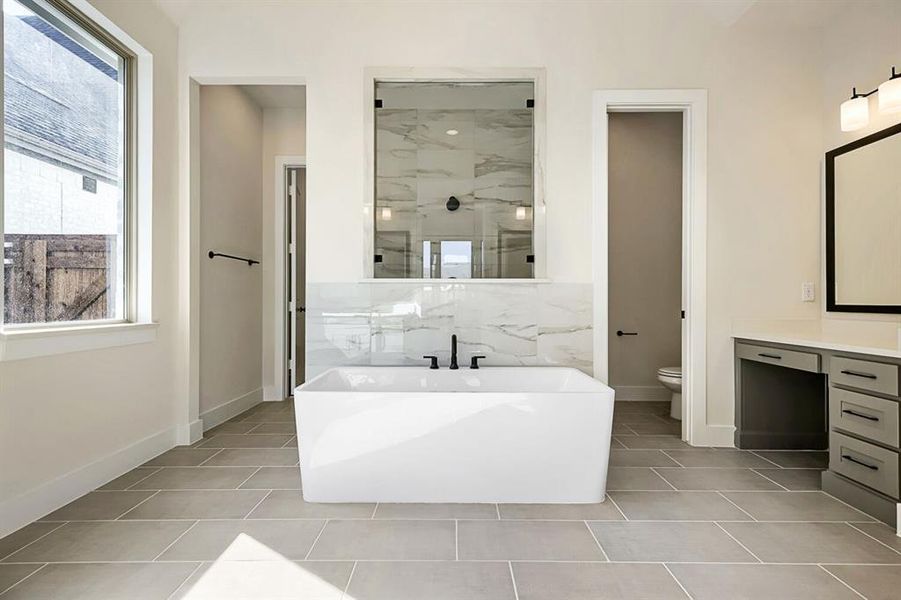 Bathroom featuring a marble finish shower, a freestanding bath, vanity, and light tile patterned floors Bathroom featuring a marble finish shower, a freestanding bath, vanity, and light tile patterned floors
