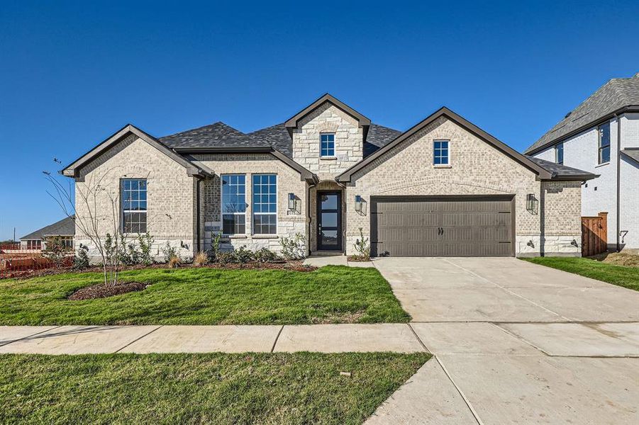 French country inspired facade featuring a garage and a front lawn