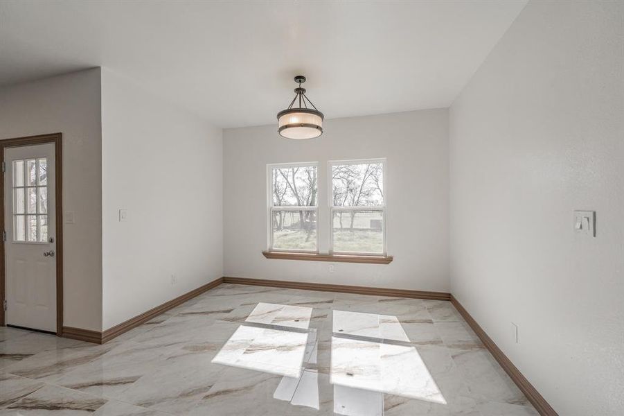 Unfurnished dining area with marble finish floor and baseboards