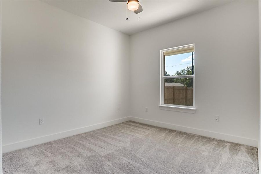 Carpeted empty room featuring baseboards and ceiling fan