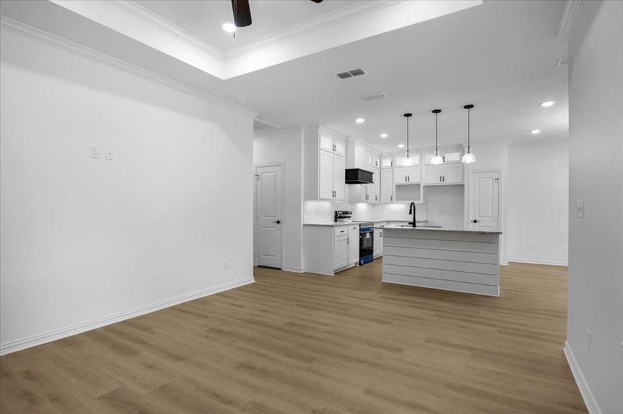 Kitchen with recessed lighting, white cabinetry, hanging light fixtures, range with electric cooktop, and a kitchen island with sink