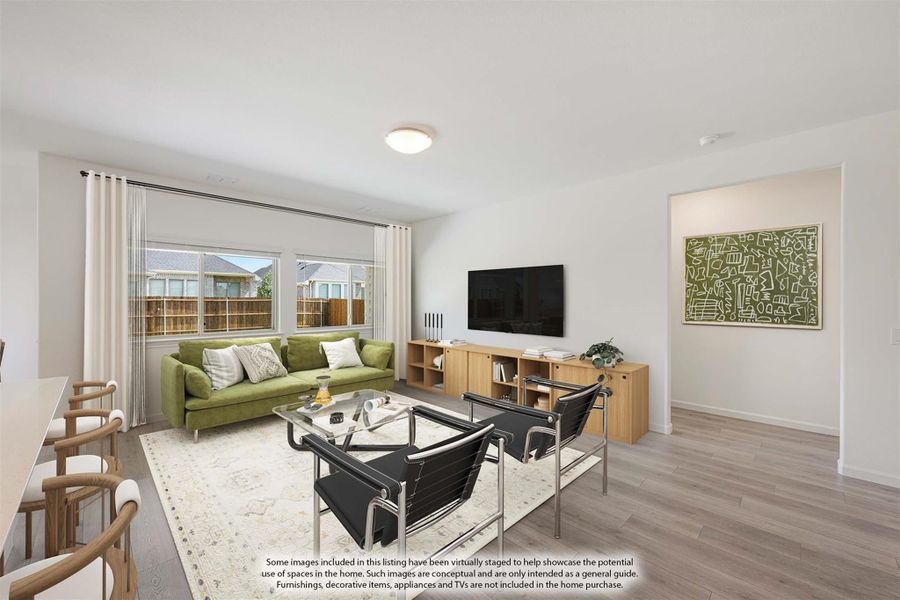Living room with green sofa, wall-mounted TV, wood floors, and large windows with white curtains Living room with green sofa, wall-mounted TV, wood floors, and large windows with white curtains
