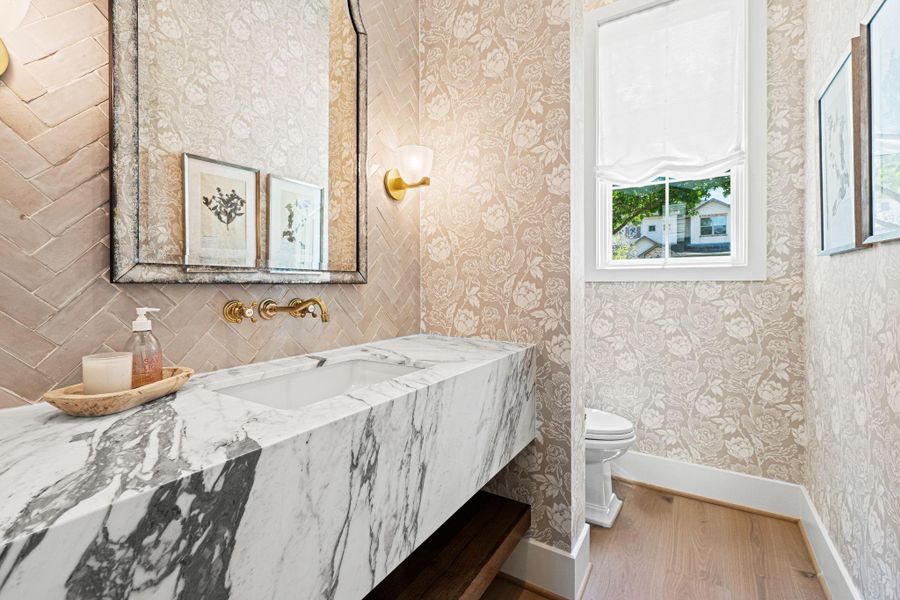 Located on the first floor, this gorgeous powder bath offers a striking, design-forward moment. A marble waterfall edge floating vanity pairs w/ wall-mounted plumbing fixtures, while a Zellige tile backsplash extends to the ceiling for added texture. Designer Farrow & Ball wallpaper & Visual Comfort sconces complete the space, creating a refined setting for guests. Located on the first floor, this gorgeous powder bath offers a striking, design-forward moment. A marble waterfall edge floating vanity pairs w/ wall-mounted plumbing fixtures, while a Zellige tile backsplash extends to the ceiling for added texture. Designer Farrow & Ball wallpaper & Visual Comfort sconces complete the space, creating a refined setting for guests.