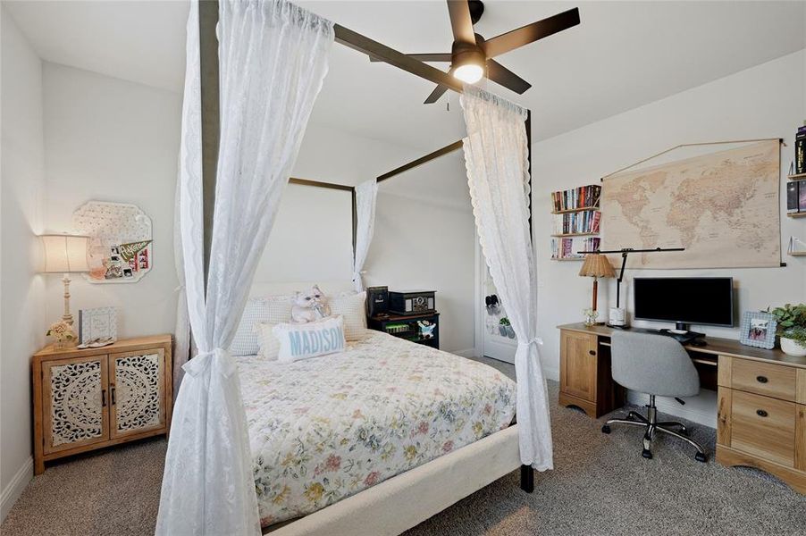 Bedroom space featuring a contemporary ceiling fan, an integrated desk and shelving unit, and wall-to-wall carpeting